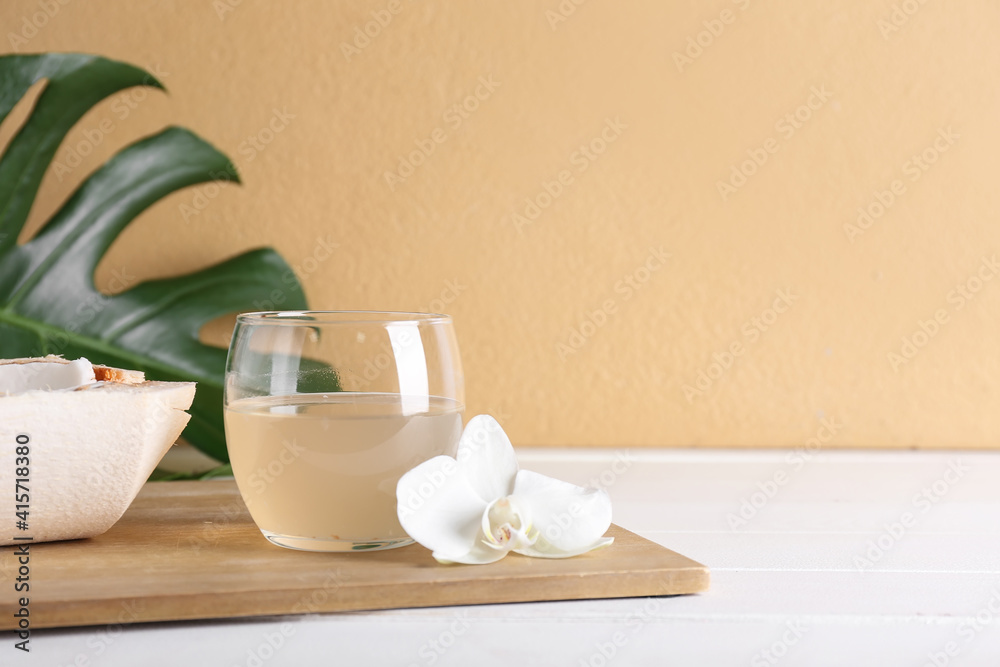 Glass of tasty coconut water on light wooden background