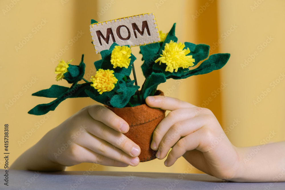 Topper pick with words Mom in felt yellow handmade dandelions in the childrens hands on a yellow te