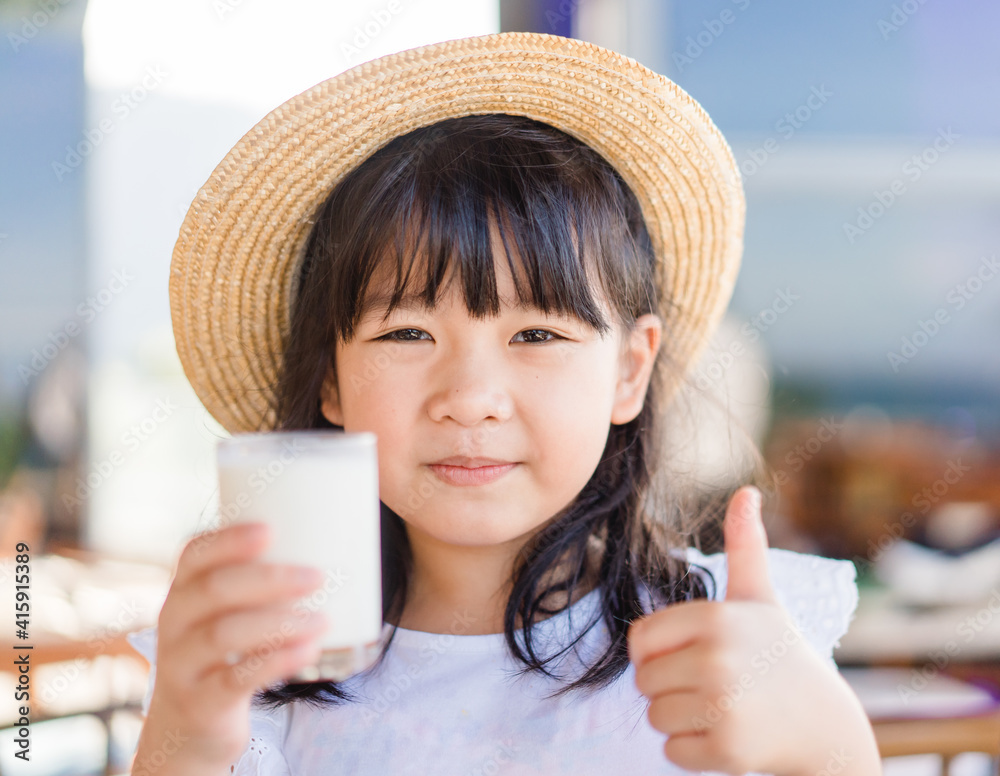 玻璃上的新鲜有机无乳糖牛奶。亚洲可爱的小女孩喝牛奶。来自m的钙维生素