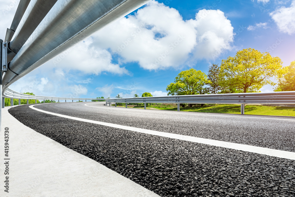 空旷的道路和蓝天下的绿树。