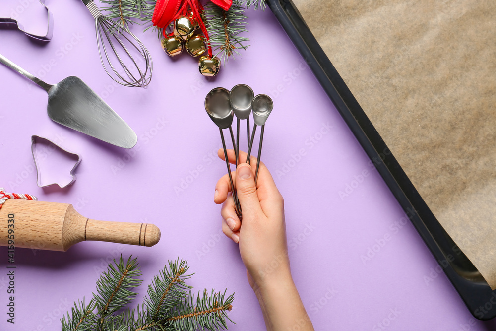 Female hand with measuring spoons on color background