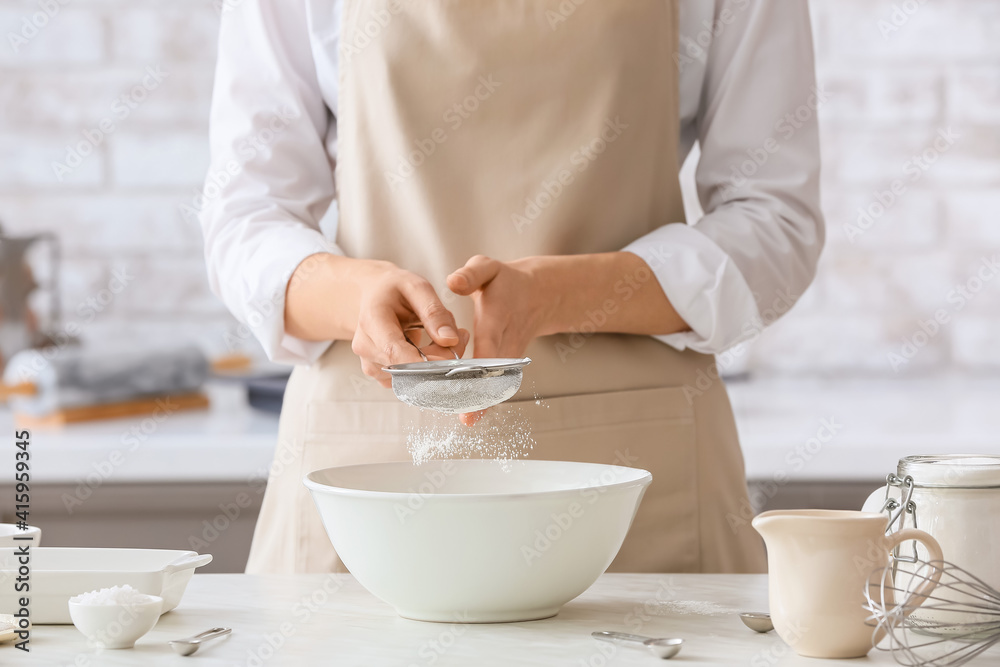 Woman making dough on table in kitchen