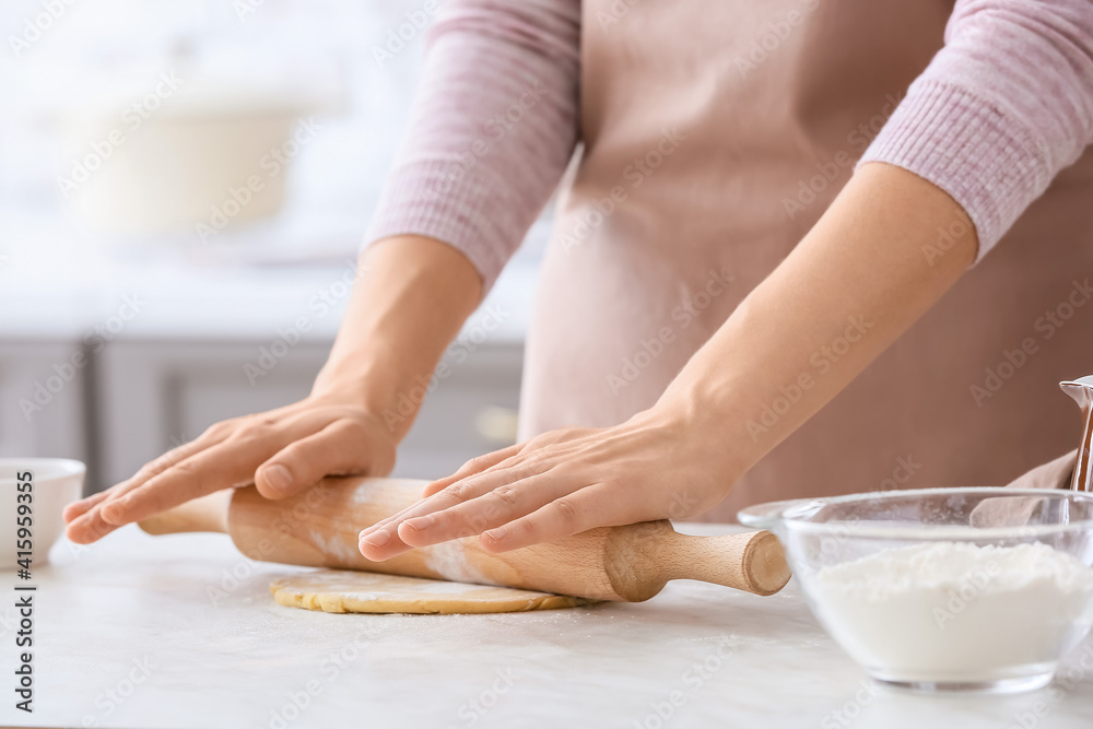 Woman making dough on table in kitchen