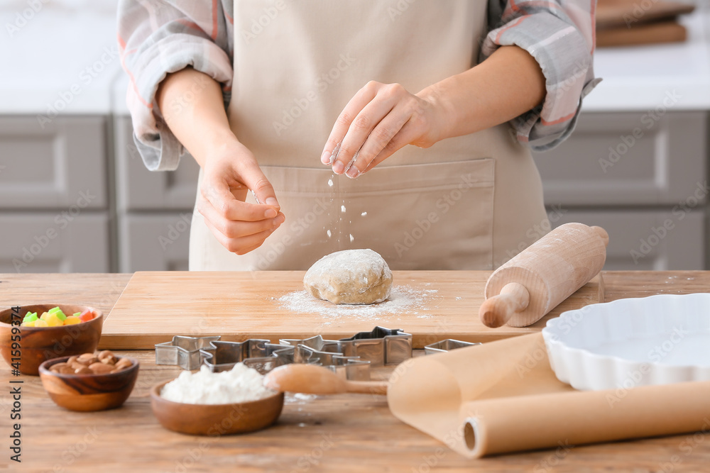 Woman making cookies on table in kitchen