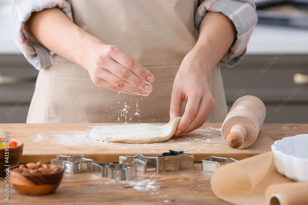 Woman making cookies on table in kitchen