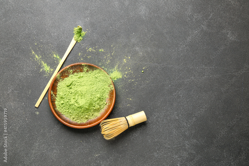 Plate with powdered matcha tea, chashaku and chasen on dark background