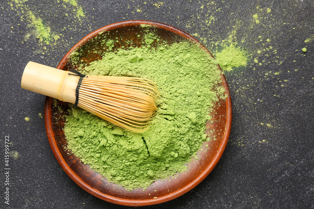 Plate with powdered matcha tea and chasen on dark background, closeup