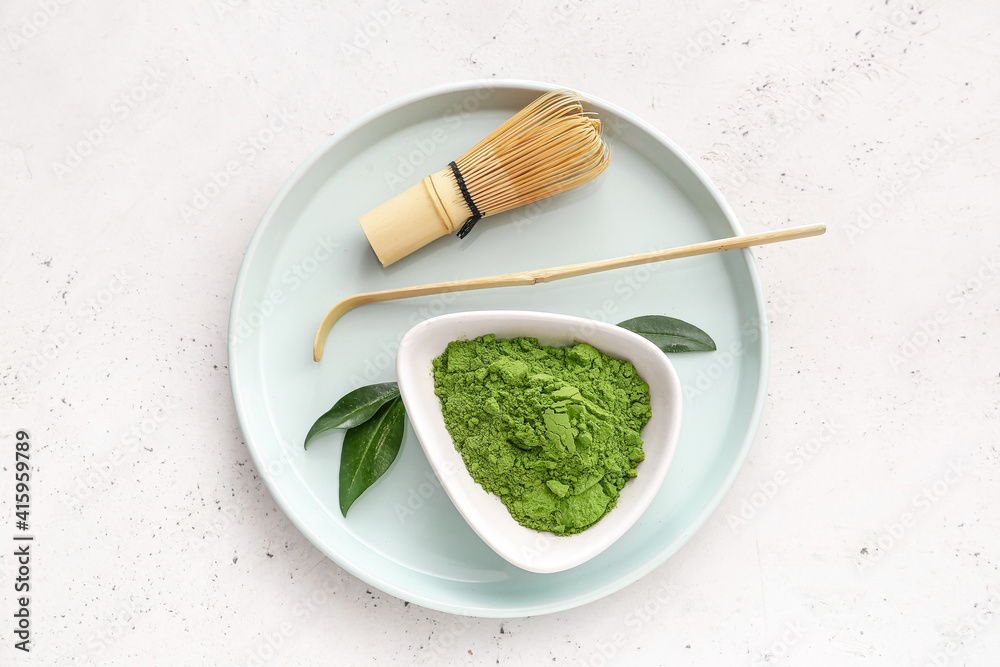 Tray with powdered matcha tea, chashaku and chasen on light background