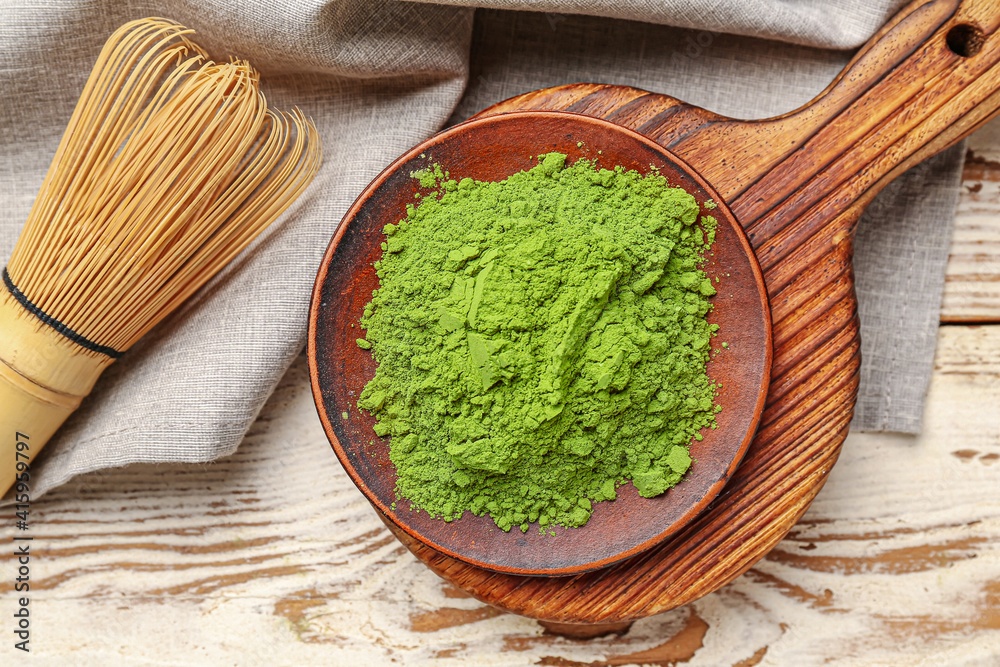 Composition with powdered matcha tea on light wooden background