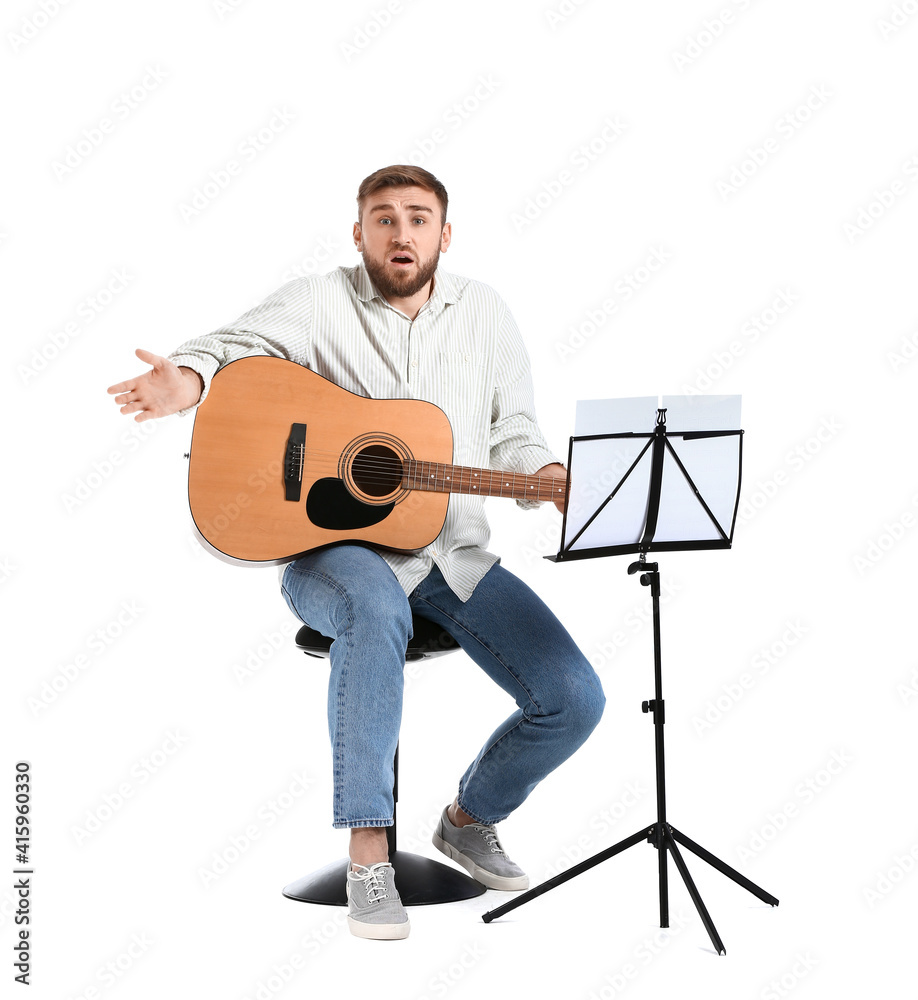 Troubled young man playing guitar on white background