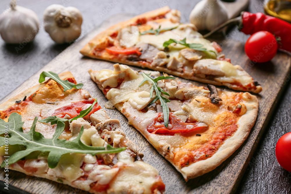 Board with slices of tasty pizza on dark background