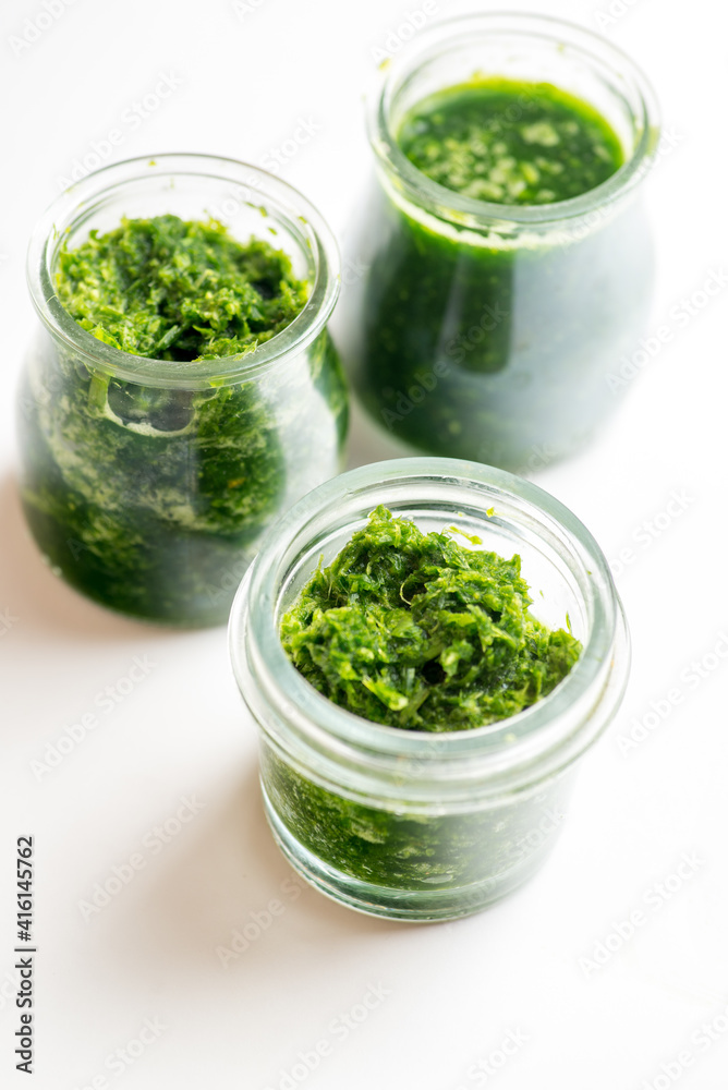 Pesto sauce in three jars on a white background