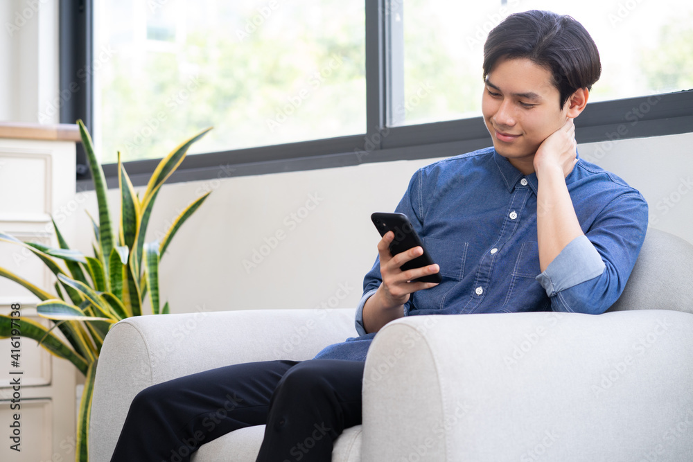 Young Asian man using the phone in the living room