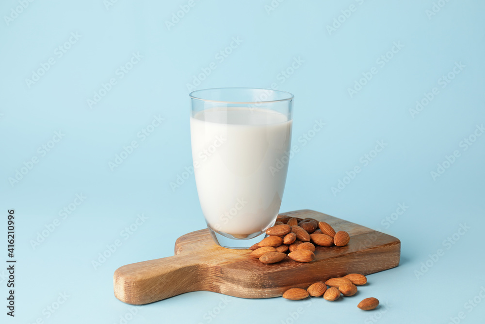 Glass of tasty almond milk on color background