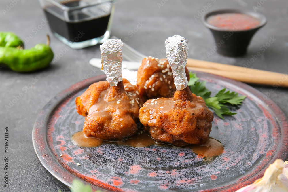 Plate with tasty chicken lollipops on dark background