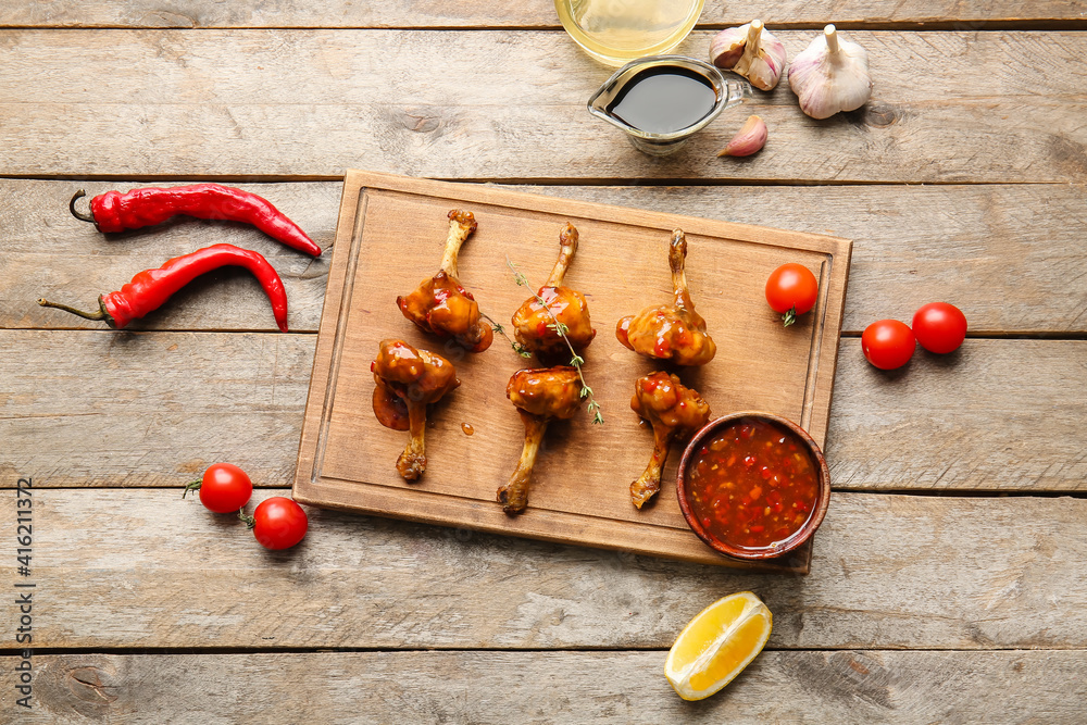 Board with tasty chicken lollipops on wooden background