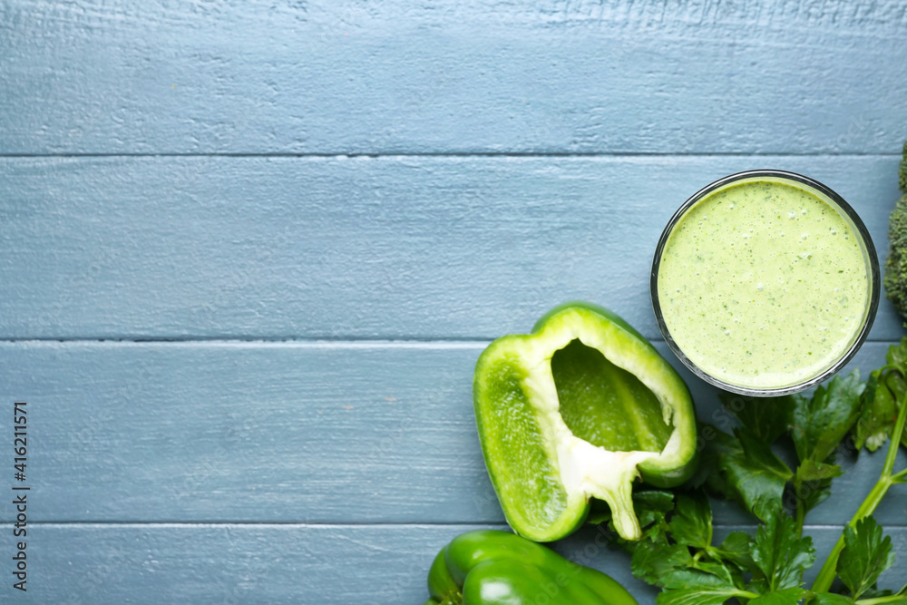 Glass of healthy smoothie with green vegetables on color wooden background