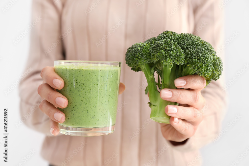 Woman with glass of healthy broccoli smoothie on white background, closeup