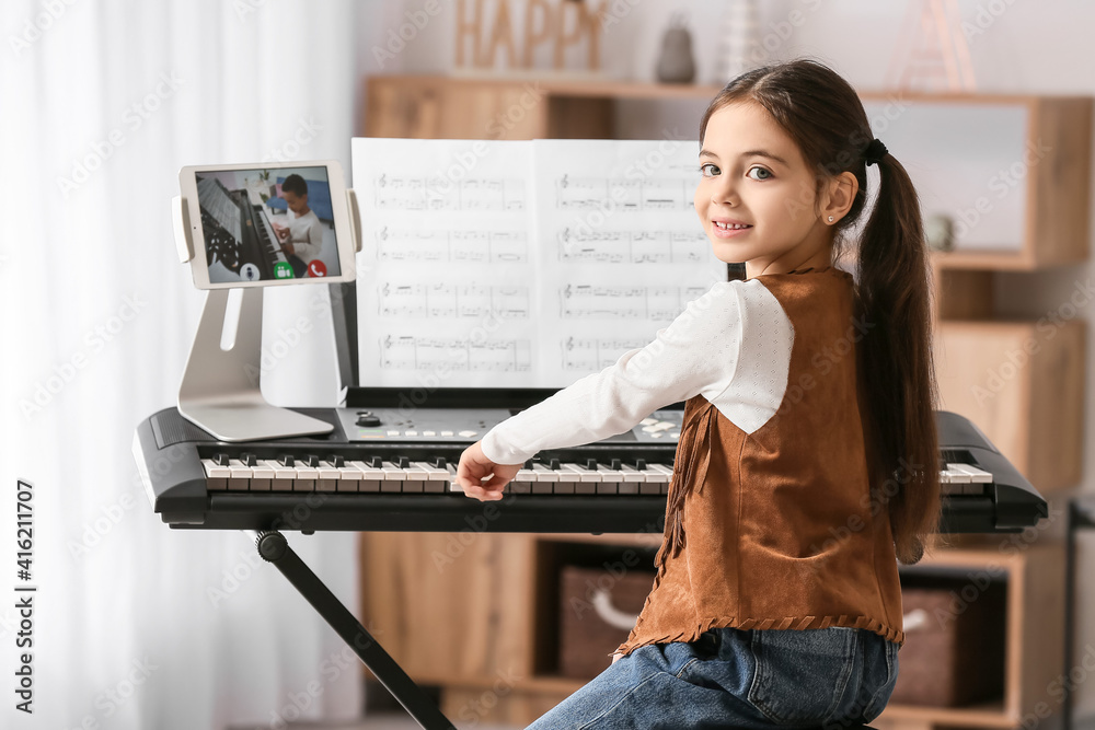 Little girl studying music with her friend online at home