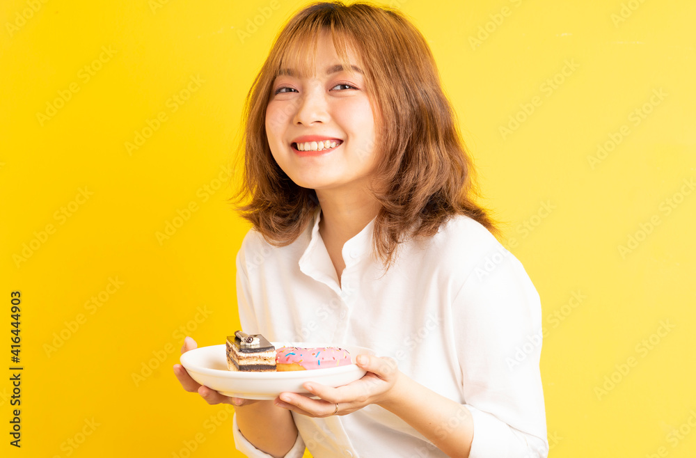 Young Asian girl holding a plate of cake with a cheerful expression