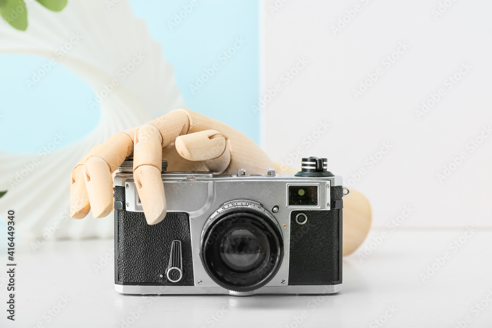 Wooden hand with photo camera on table, closeup