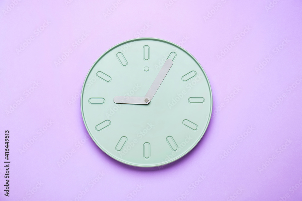 Stylish clock hanging on color wall