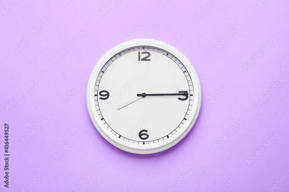 Stylish clock hanging on color wall