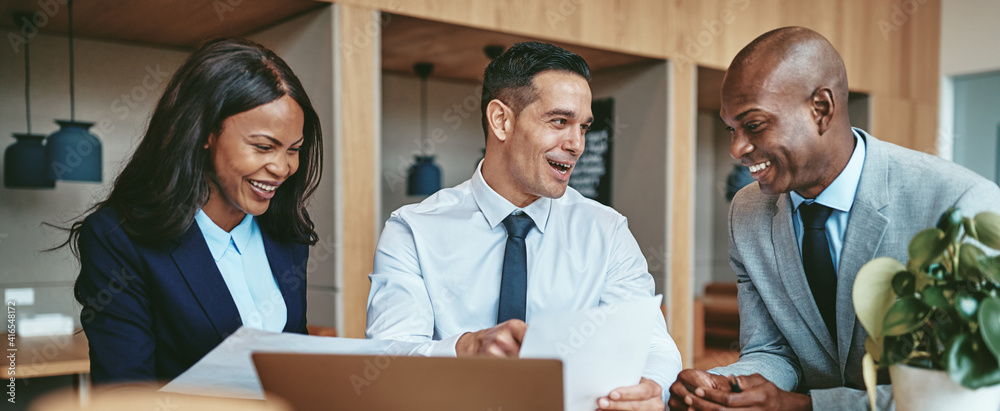 Diverse businesspeople smiling while working together at an office table