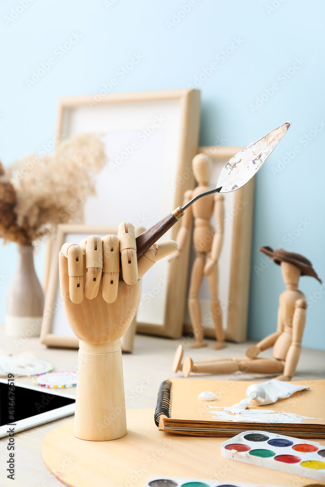 Creative composition with wooden mannequins and artist supplies on table