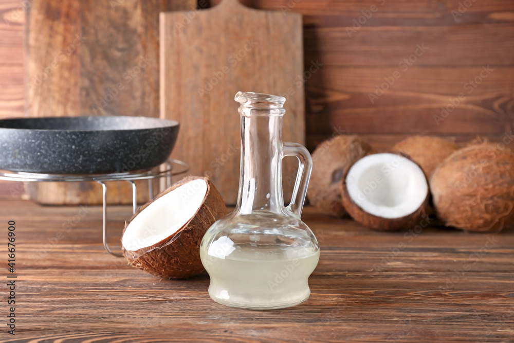 Decanter of coconut oil on wooden background