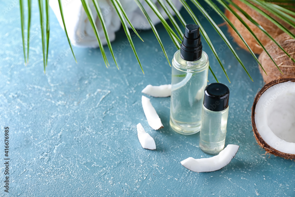 Composition with bottles of coconut oil on color background