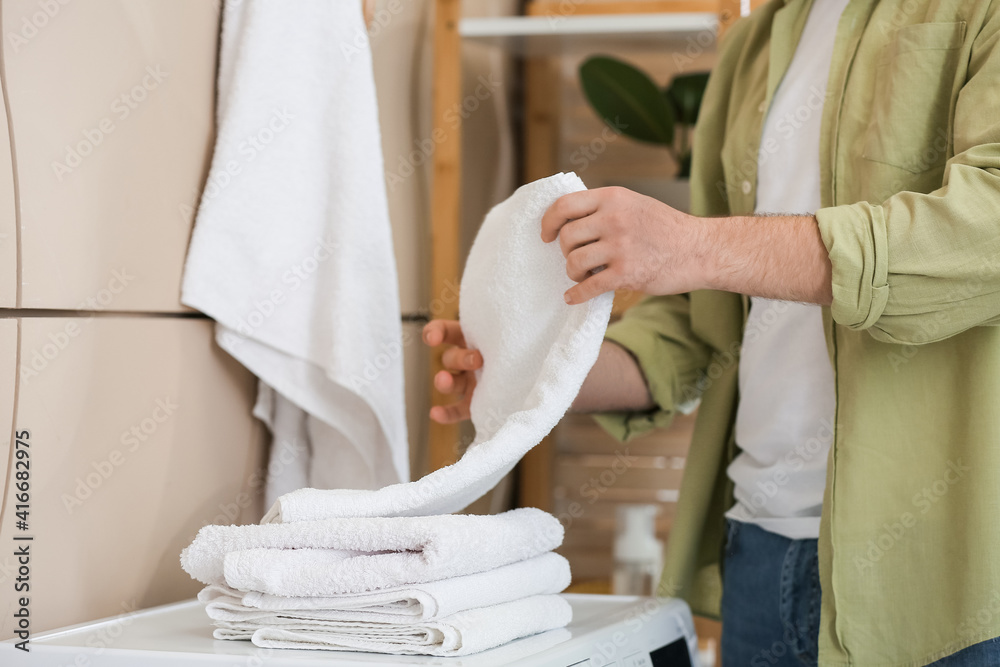 Man with clean towels in bathroom