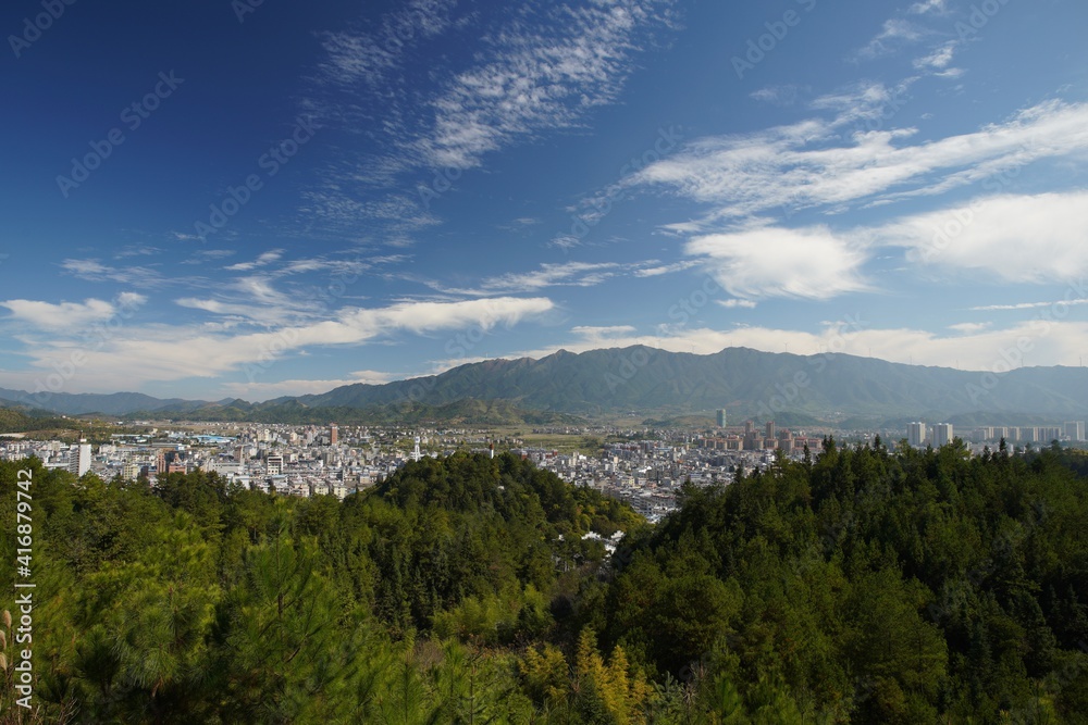 青山环抱的城市景观全景；蓝天下的城市景观