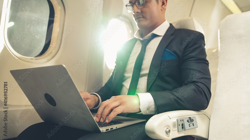 Young businessman using laptop computer in airplane . Business trip travel concept .