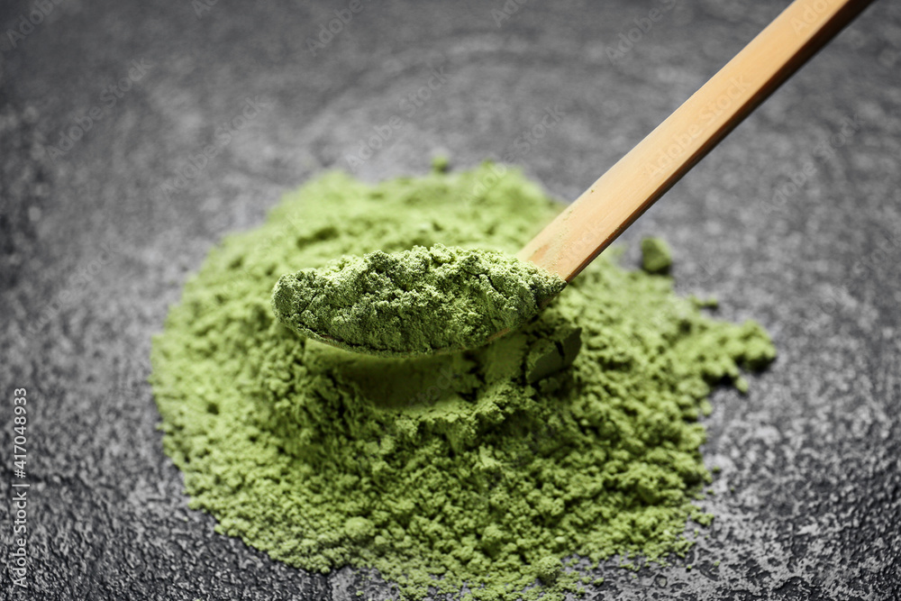 Chashaku with powdered matcha tea on dark background, closeup