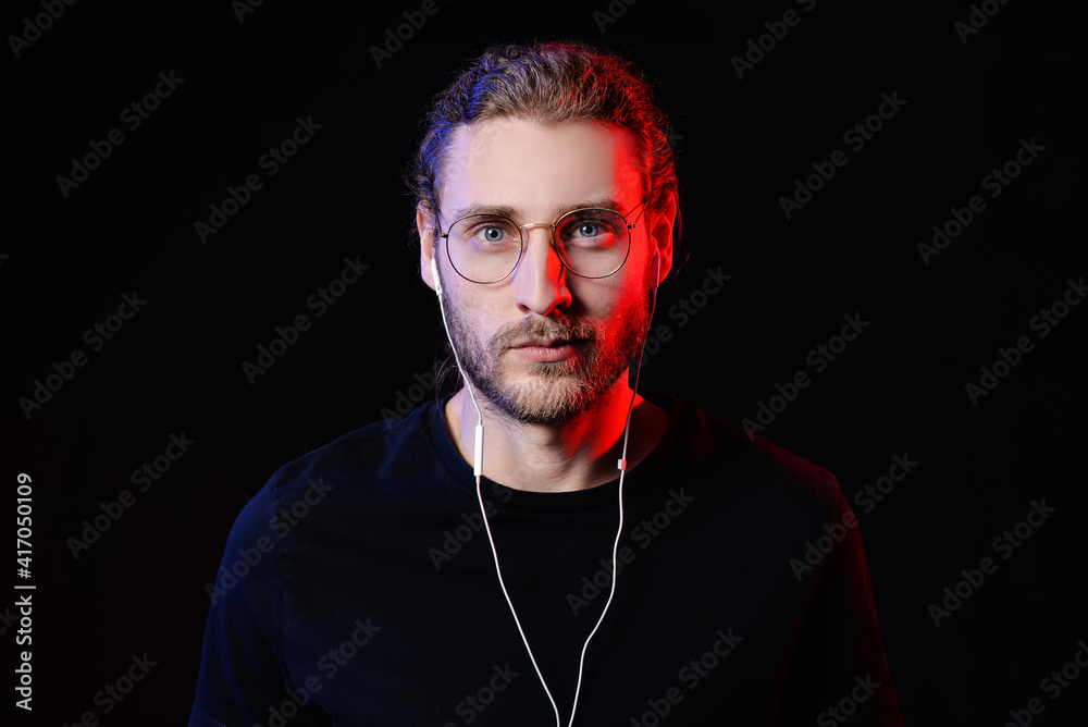 Handsome young man listening to music on dark background