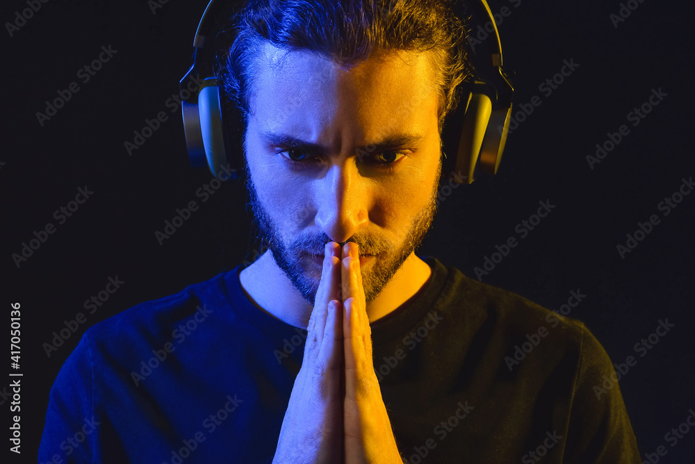 Handsome young man listening to music on dark background