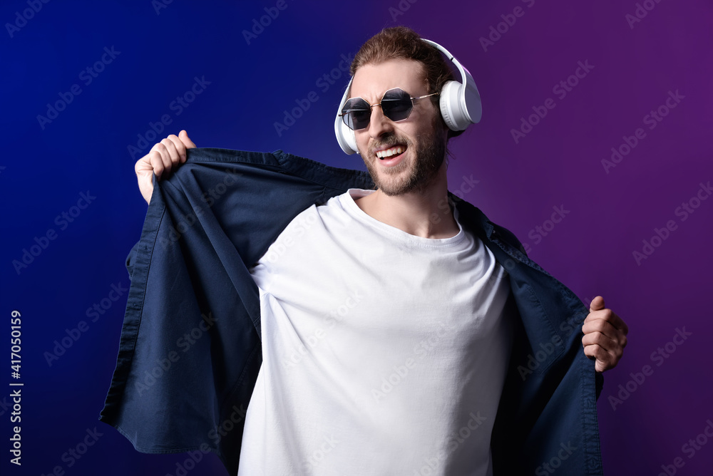 Handsome young man listening to music on dark background