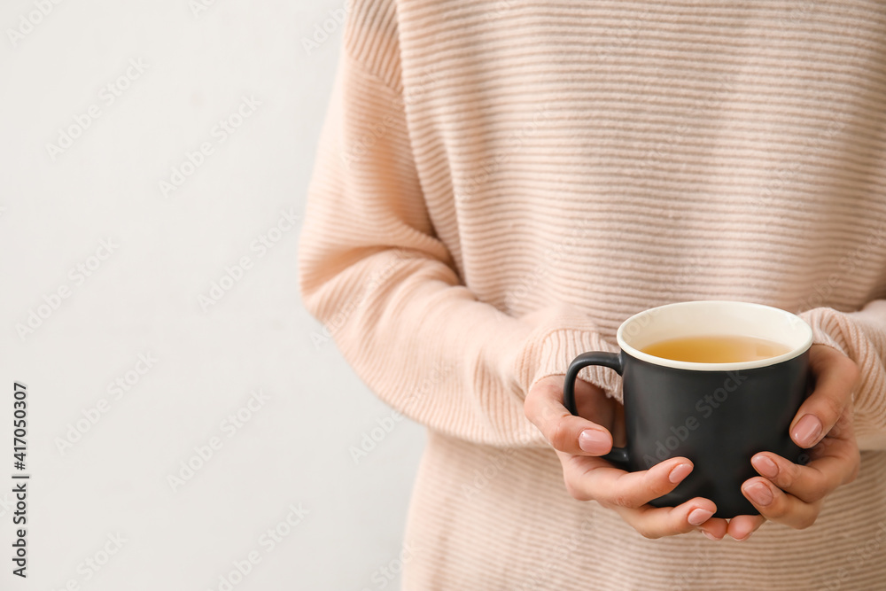 浅背景下喝着一杯热茶的女人