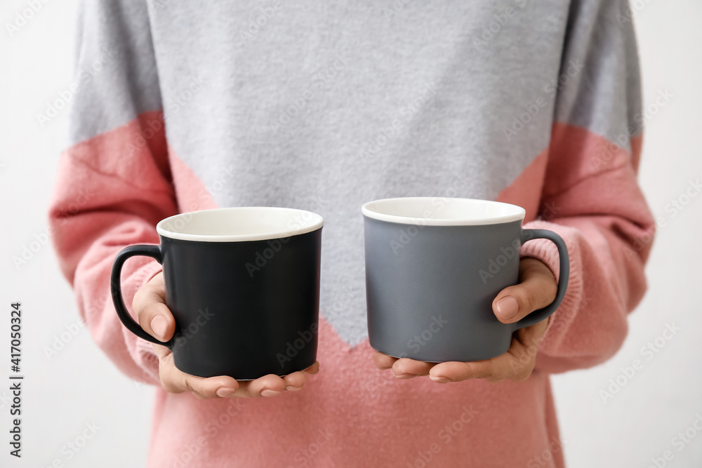 Woman with cups on light background