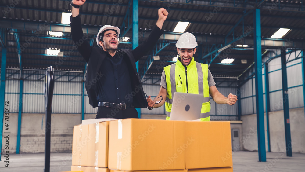 Two factory worker celebrate success together in the factory or warehouse . Industry work achievemen