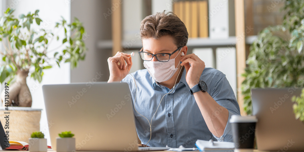 man in face mask is working on a laptop