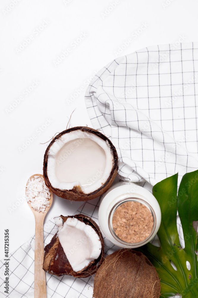 Coconut milk in glass bottle. Whole and cracked coco. Flat lay, top view isolated on white