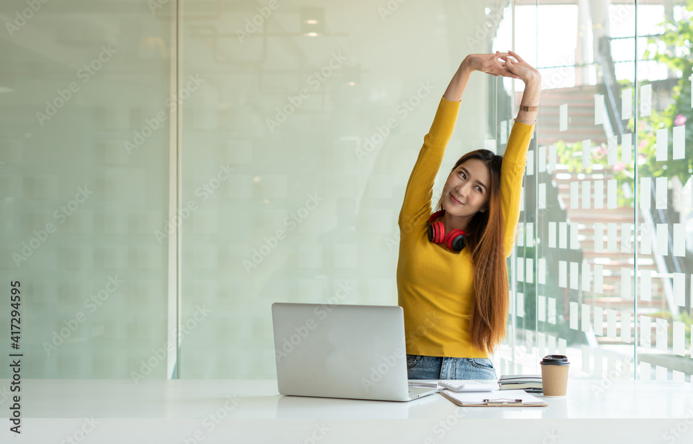 A young woman who is relaxed while working inside the office and listening to her favorite music in 