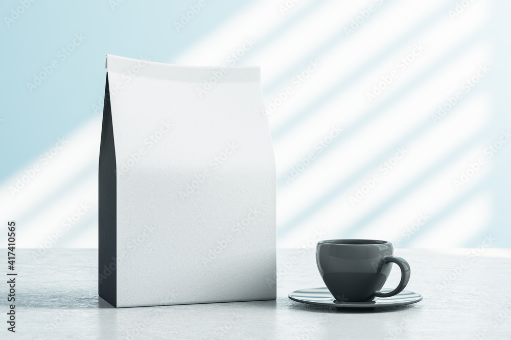 Blank white tea bag with a space for you logo and black coffee cup on light table at sunny wall back