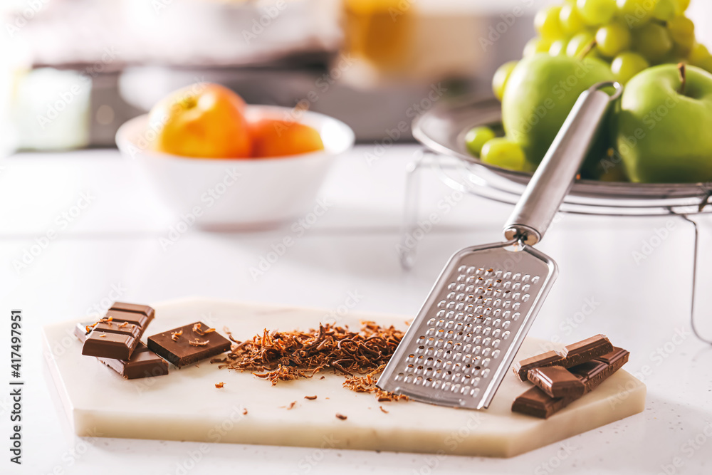 Sweet chocolate with grater on table in kitchen