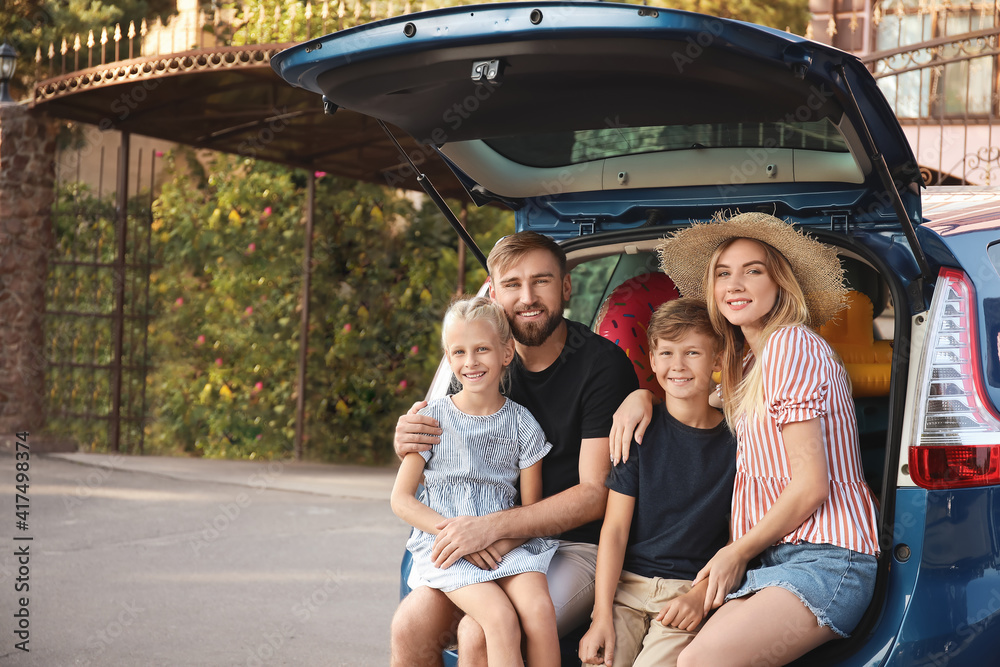 Happy family sitting in car trunk outdoors