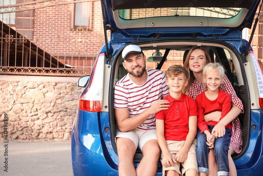 Happy family sitting in car trunk outdoors