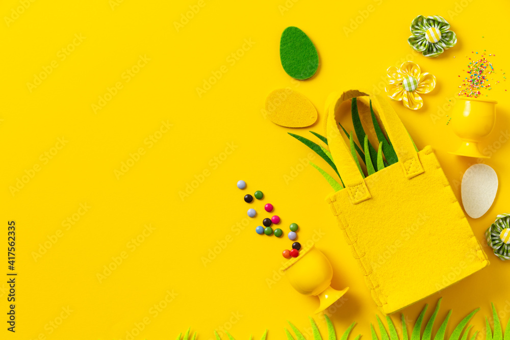 Felt Easter decorations and sweets on yellow background