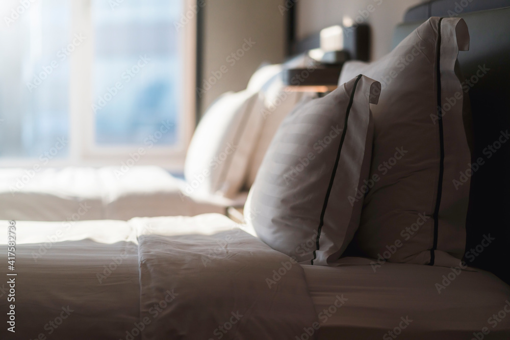 Bed maid-up with clean white pillows and bed sheets in beauty room. Close-up. Lens flair in sunlight